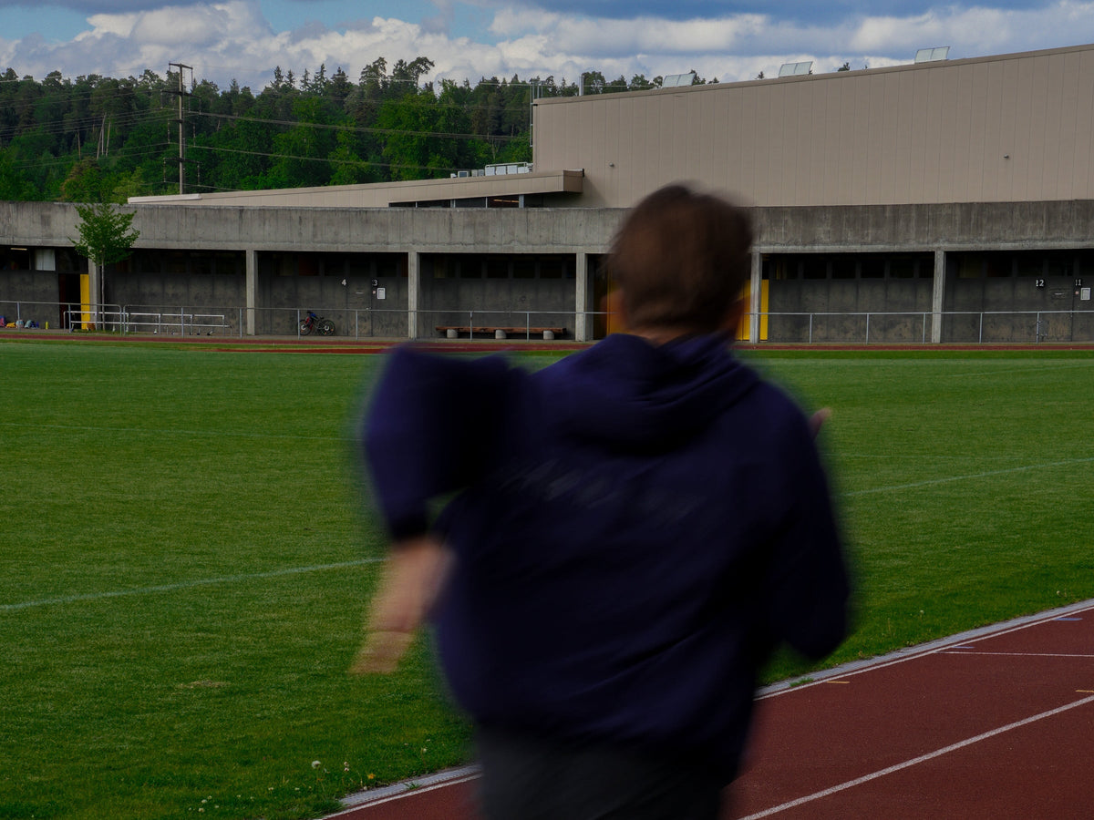 Läufer im Athlix Windbreaker auf der Tartanbahn mit Motion Blur – Brick-Training vom Rad aufs Laufen