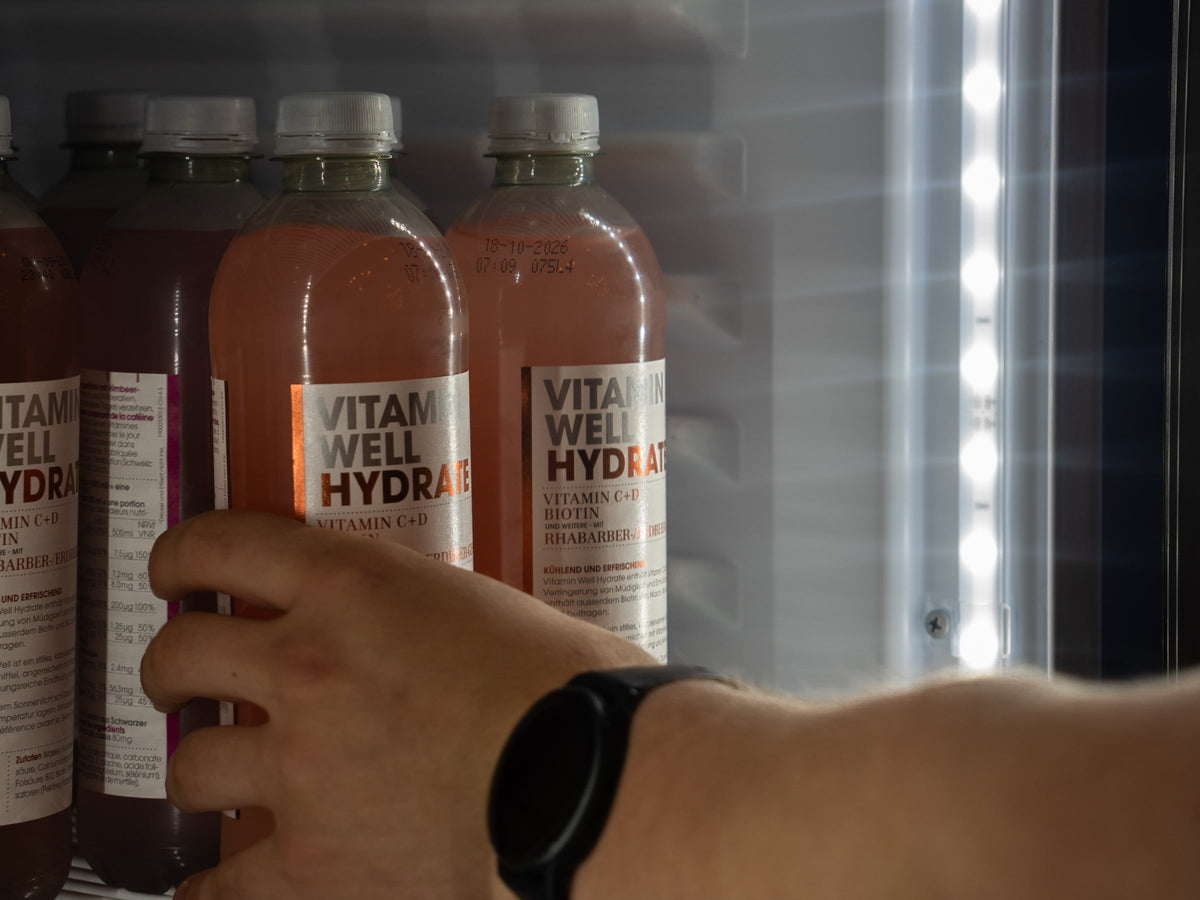 Hand greift nach einem Elektrolyt-Getränk im Kühlschrank – Hydration nach dem Training