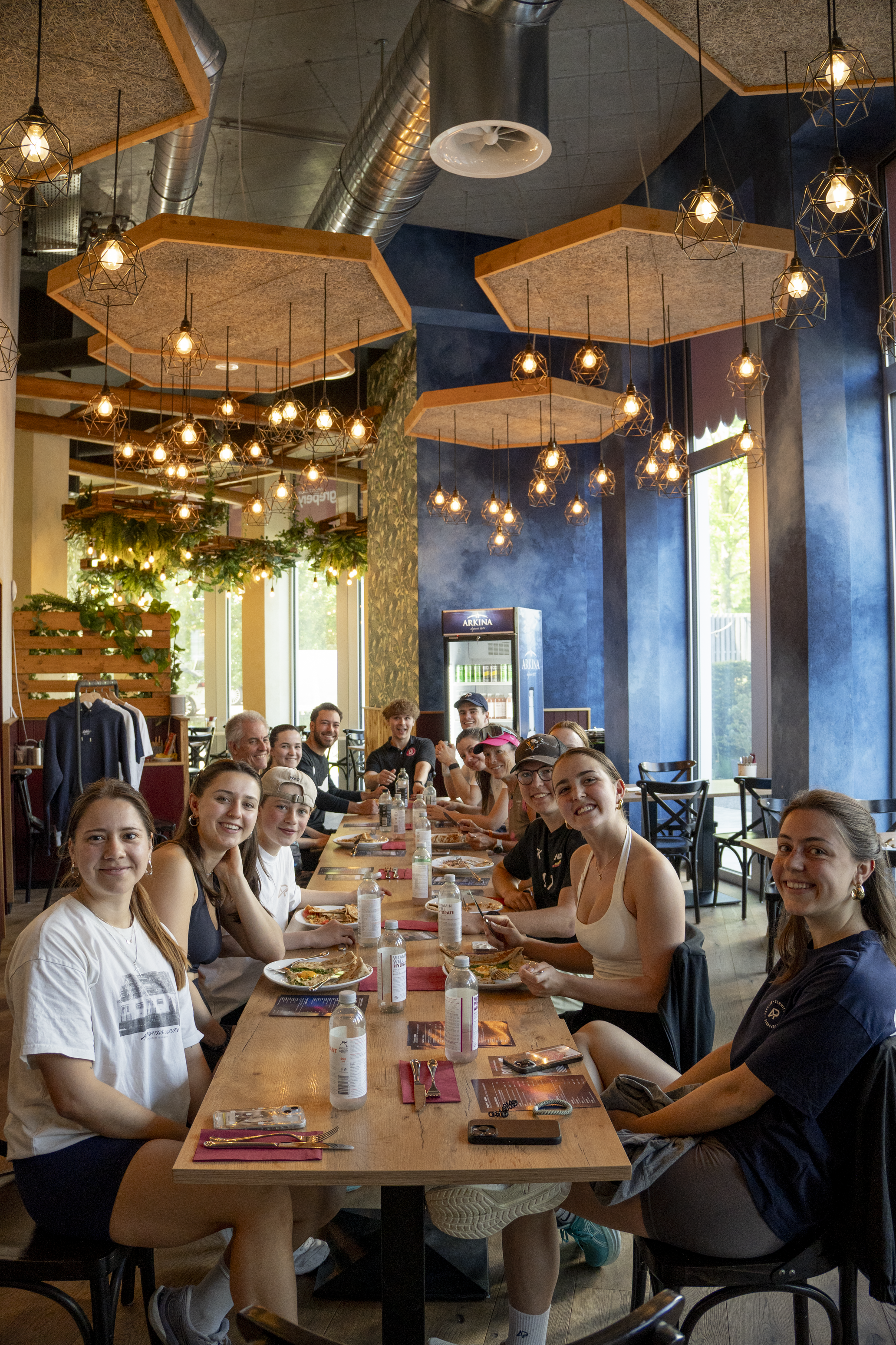 Athlix Community sitzt nach dem Lauf gemeinsam an einer langen Tafel im stilvollen Restaurant und geniesst gemeinsames Essen und Gespräche.