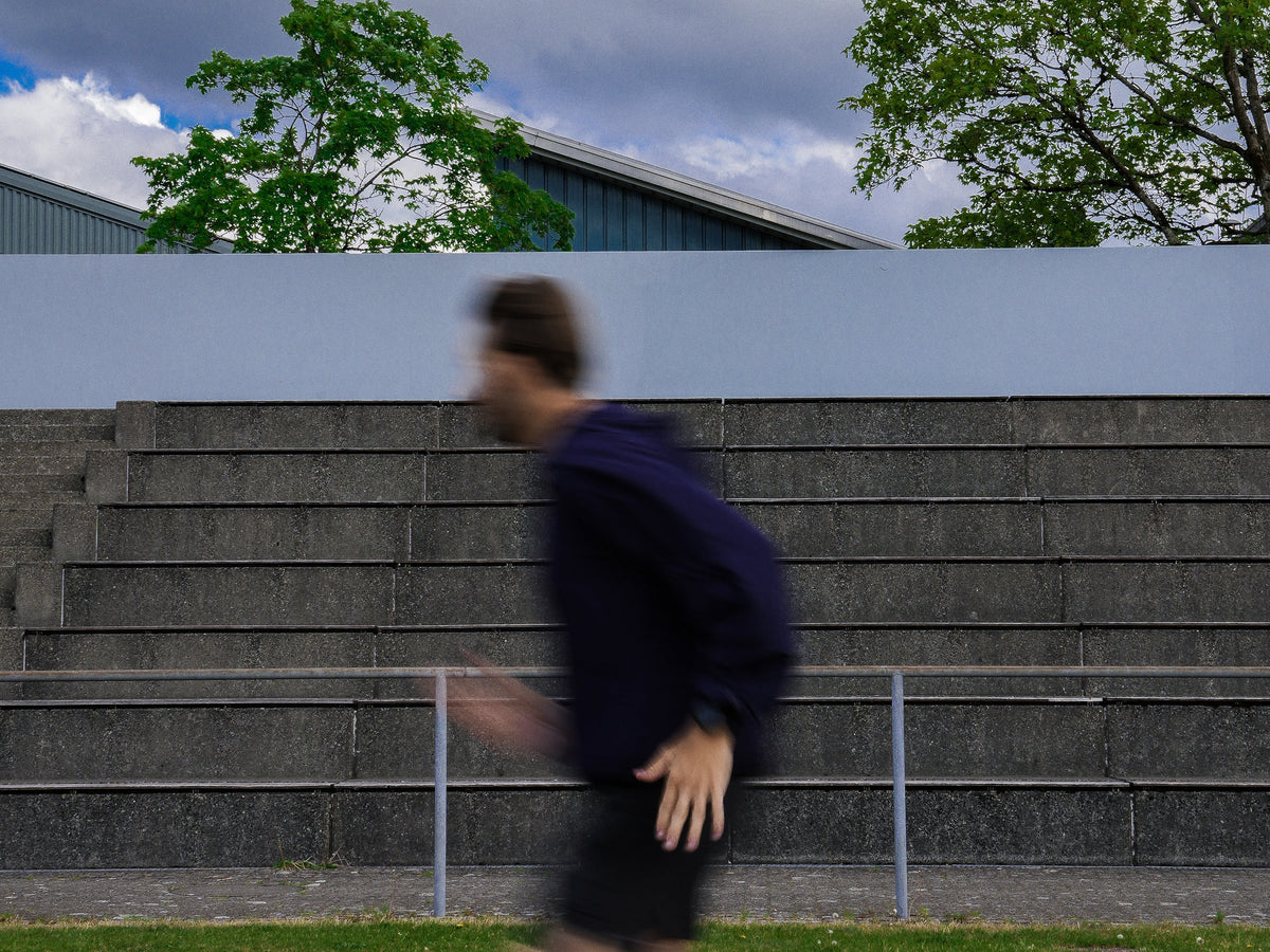 Läufer im Athlix Windbreaker sprintet auf der Tartanbahn – hohe Schrittfrequenz und sauberer Laufrhythmus