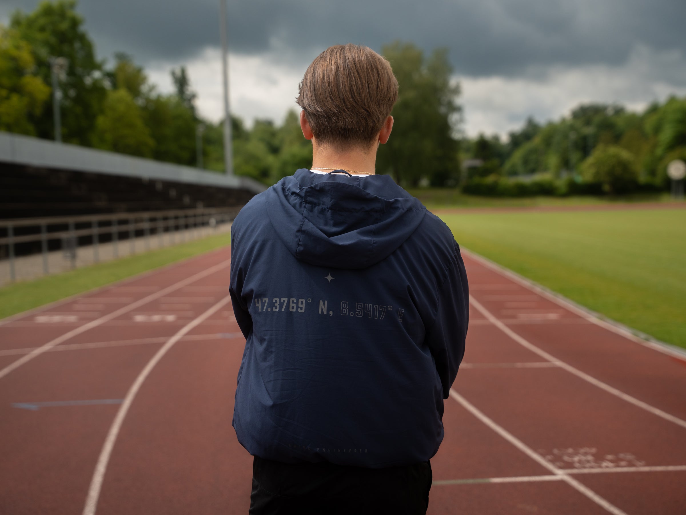Läufer im Athlix Windbreaker von hinten auf der Tartanbahn – 5K Trainingsplan