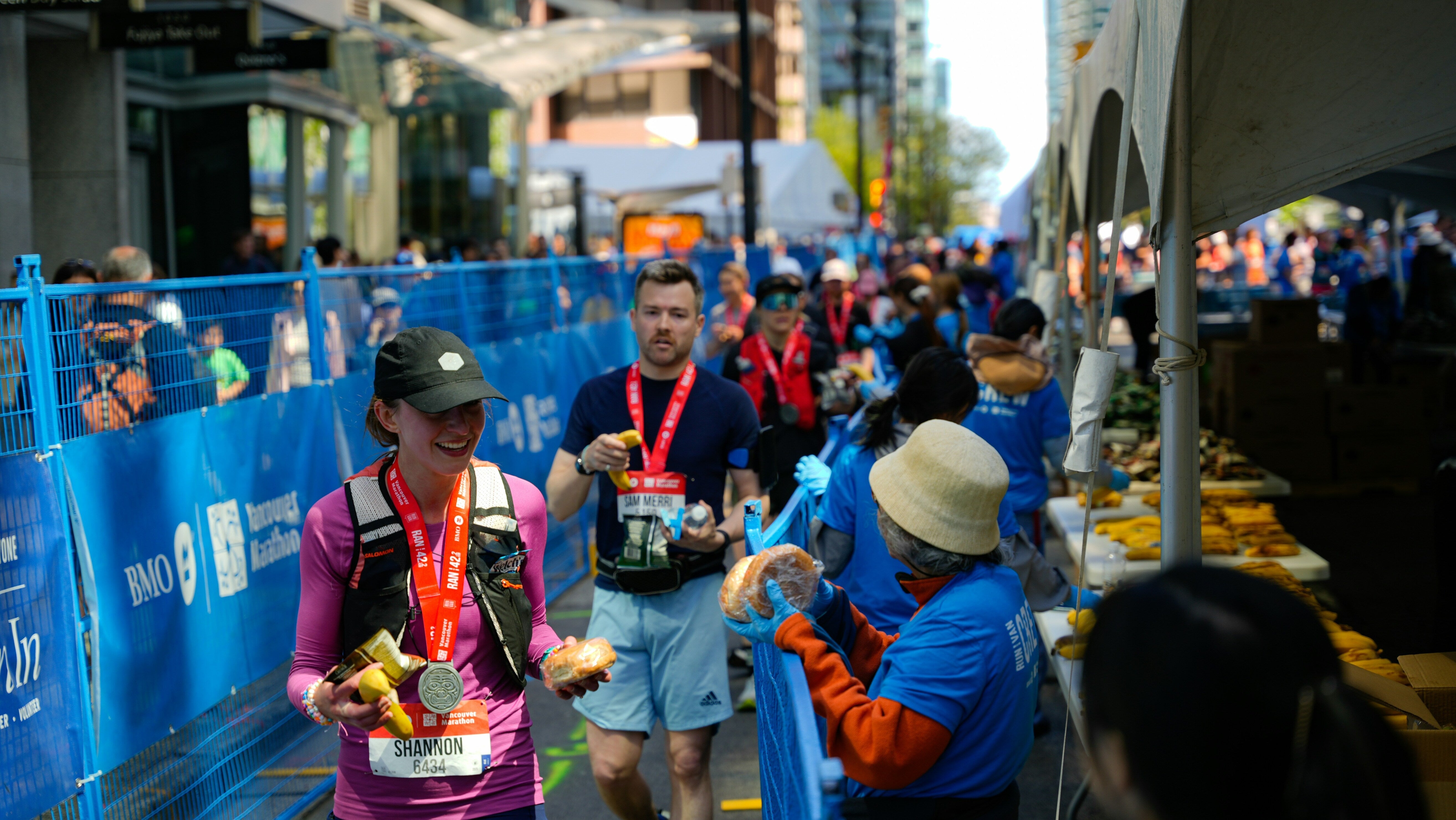 Läuferin mit Finisher-Medaille nimmt im Zielbereich eines Marathons Verpflegung entgegen