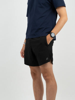 Schwarze Laufshorts mit kleinem grauem AP-Logo am Bein, Hand in der Seitentasche