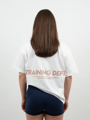 Frau von hinten im weissen T-Shirt mit kupferfarbenem Training-Dept-Print und dunkelblauen Shorts