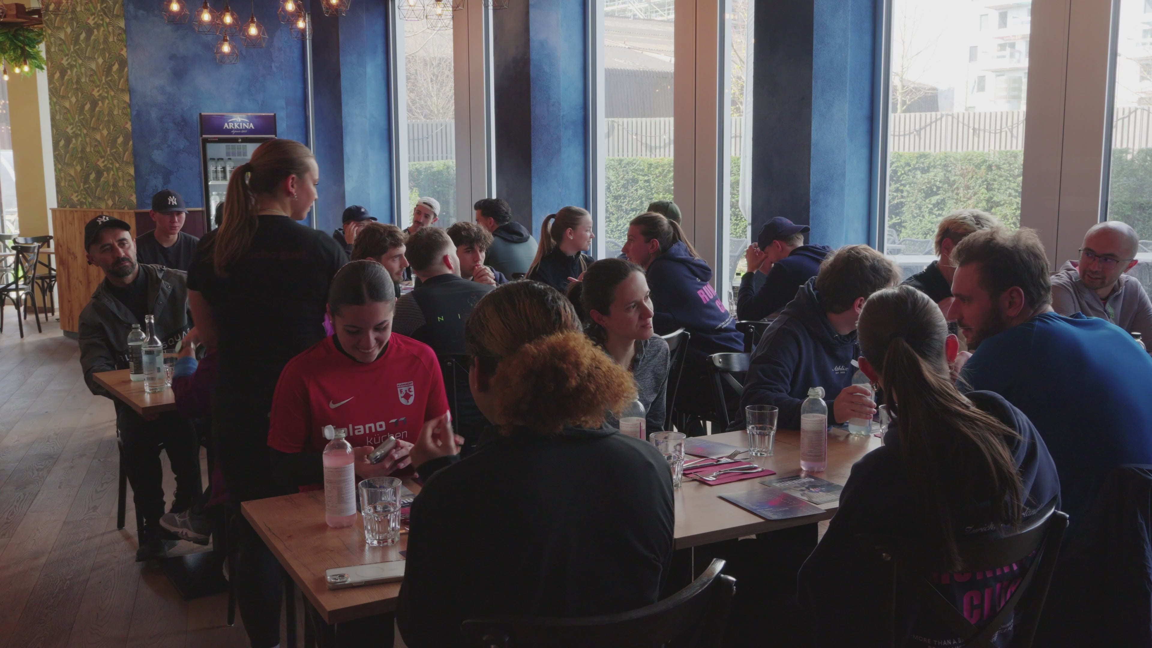 Grosse Athlix Running Club Gruppe sitzt nach dem Lauf gemeinsam im Restaurant und geniessen gemeinsames Essen und Gesellschaft.